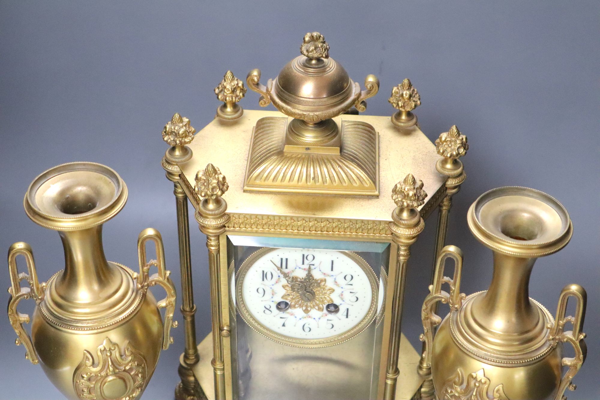 A late 19th century French garniture de cheminée comprising a four-glass mantel clock and a pair of vases